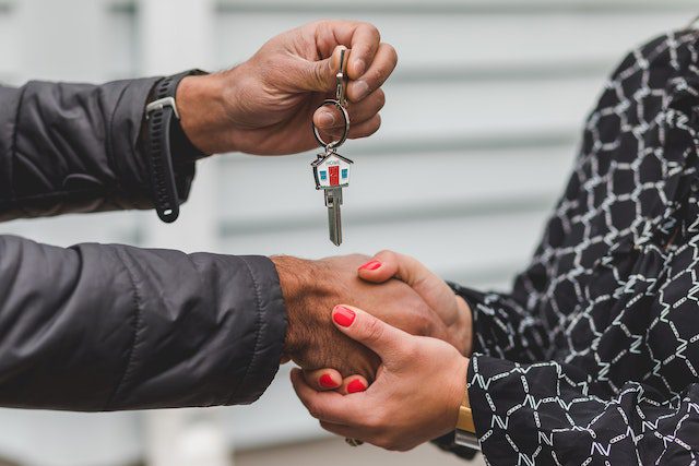 Real estate agent handing over keys to a man after buying a home on a single income