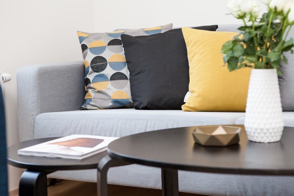 A grey sofa with colorful cushions and a black coffee table