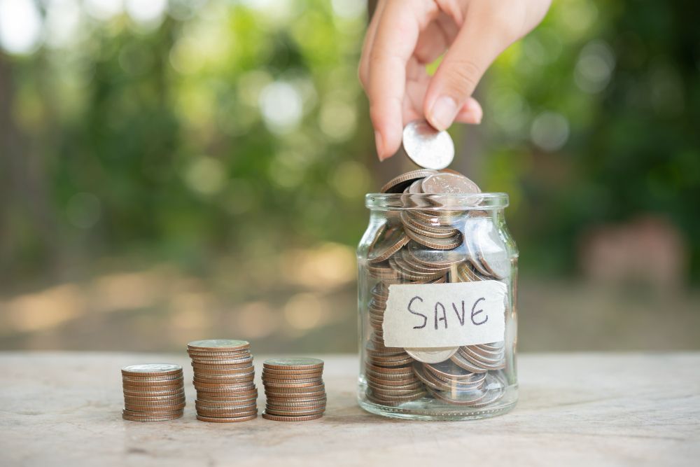 A person adding a coin to a savings jar from Eco-Friendly-Home-Features