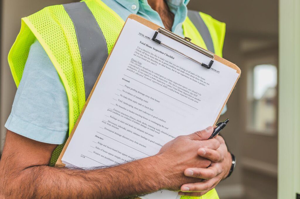 A person in a yellow vest holding an inspection list and a pen