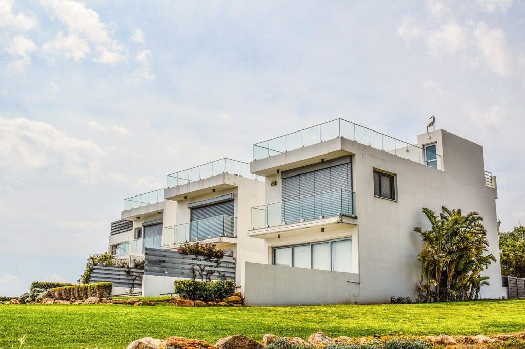 Modern white duplex homes with glass balconies and lush green landscaping