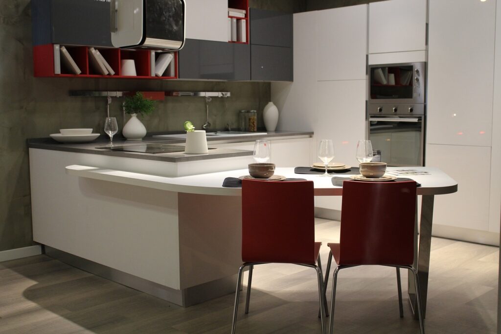 Modern kitchen with sleek cabinets, red chairs, and minimalist decor.