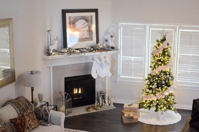 Decorated Christmas tree next to a white fireplace with a painting on top of it